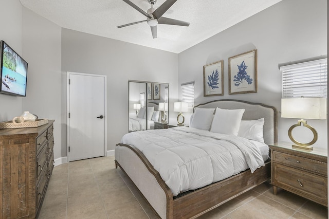 bedroom featuring light tile patterned floors, a textured ceiling, baseboards, and ceiling fan