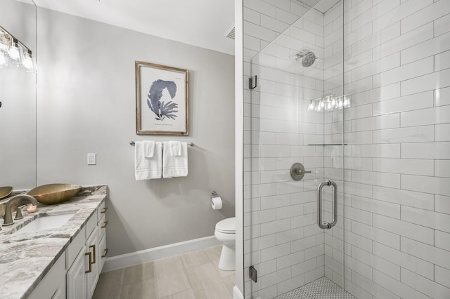 full bath with toilet, a stall shower, vanity, and baseboards
