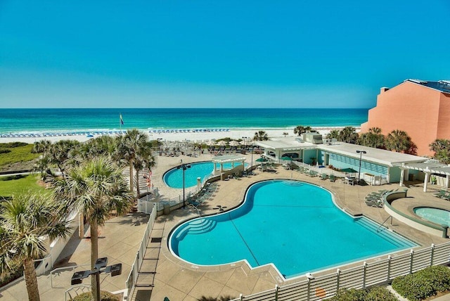 pool with a beach view, a pergola, a water view, fence, and a patio