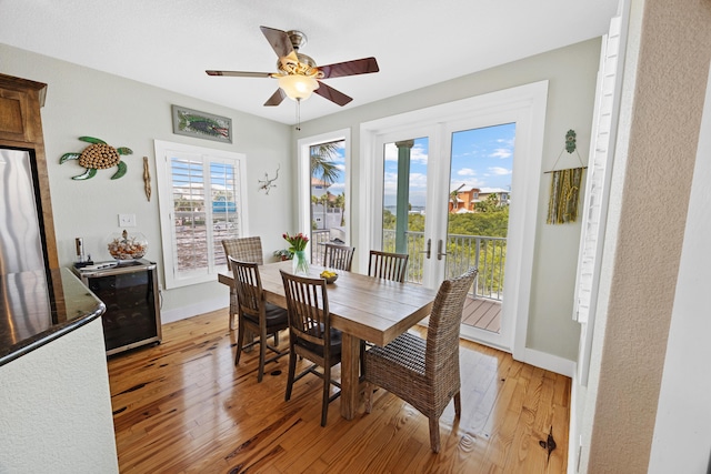 dining room with light wood-style flooring, wine cooler, baseboards, and a ceiling fan