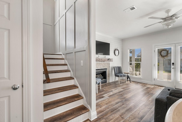 stairway with visible vents, baseboards, a ceiling fan, a fireplace, and wood finished floors
