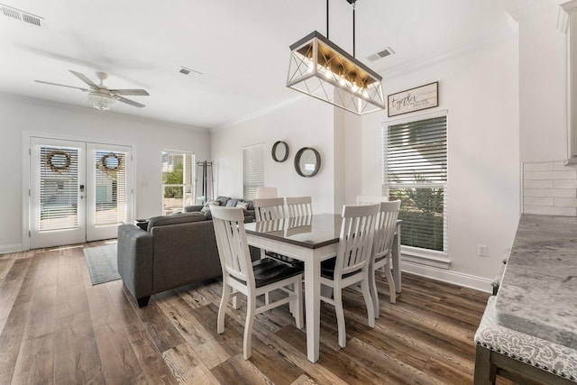 dining space with dark wood-type flooring, visible vents, and crown molding