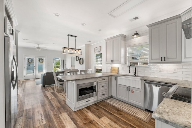 kitchen with dark wood finished floors, tasteful backsplash, a peninsula, visible vents, and appliances with stainless steel finishes