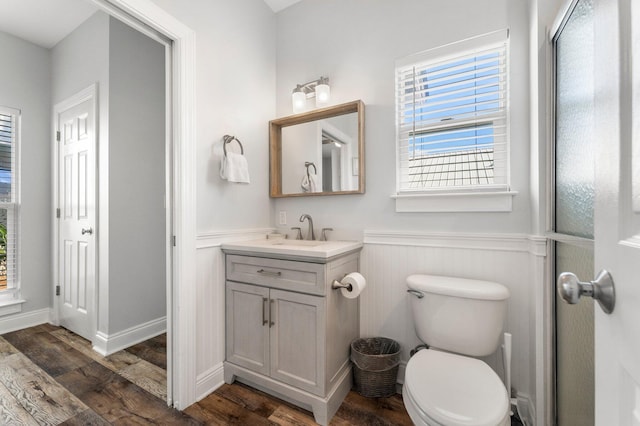 bathroom with toilet, wainscoting, wood finished floors, and vanity