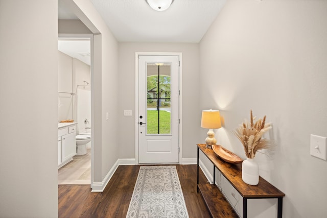 foyer entrance featuring dark wood-style floors and baseboards