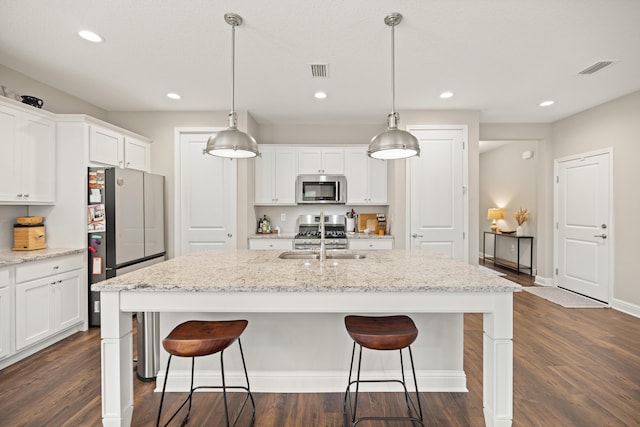 kitchen featuring dark wood-style floors, a breakfast bar, white cabinetry, and appliances with stainless steel finishes