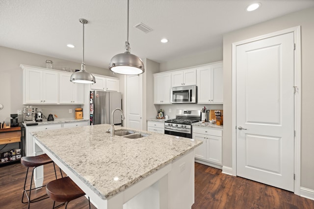 kitchen featuring dark wood-type flooring, visible vents, a sink, stainless steel appliances, and a breakfast bar area