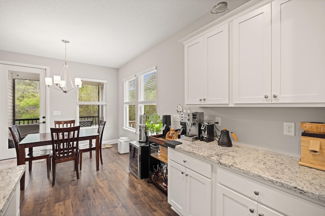 kitchen with white cabinets, light stone countertops, a notable chandelier, and dark wood finished floors