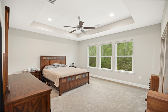 bedroom featuring light carpet, visible vents, baseboards, and a raised ceiling