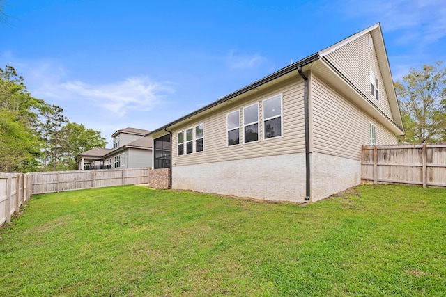 rear view of house featuring a yard and a fenced backyard
