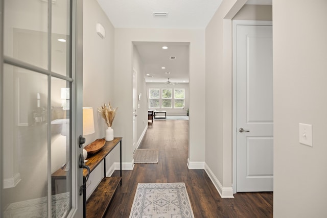 hall with visible vents, baseboards, recessed lighting, and dark wood finished floors