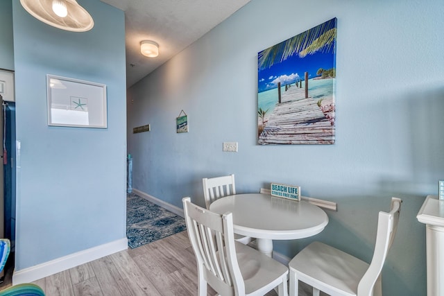 dining space with baseboards and wood finished floors