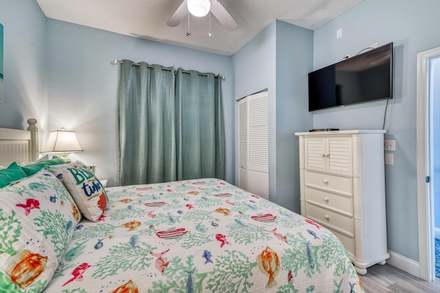 bedroom featuring ceiling fan, a closet, baseboards, and wood finished floors