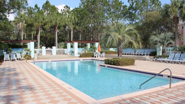 community pool featuring a patio, a pergola, and fence