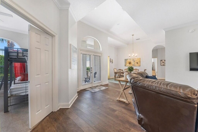 entrance foyer featuring dark wood-type flooring, arched walkways, ornamental molding, and plenty of natural light