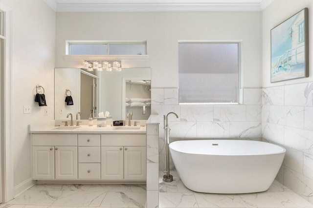 full bathroom with marble finish floor, a freestanding bath, double vanity, and a sink