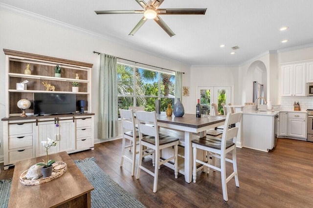 dining space featuring dark wood-style flooring, recessed lighting, crown molding, ceiling fan, and arched walkways