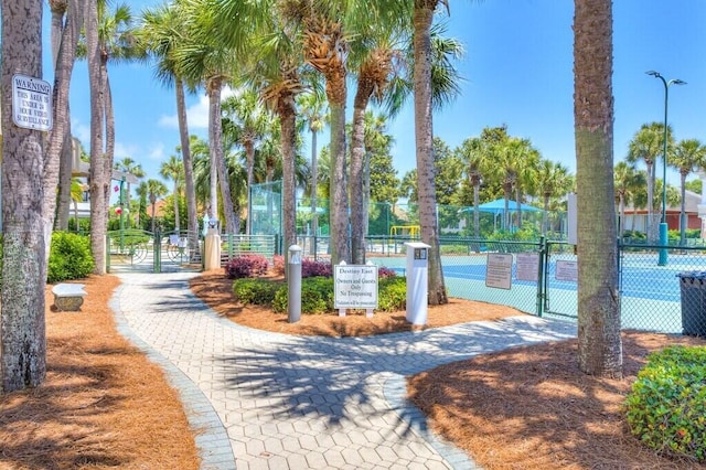 view of home's community with a tennis court, fence, and a gate