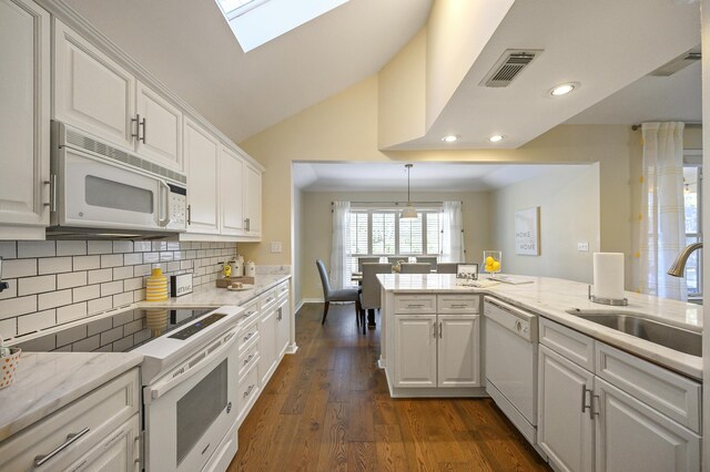 8855 Baypine Dr, Miramar Beach, FL 32550 - kitchen featuring white cabinets, visible vents, backsplash, vaulted ceiling with skylight, and white appliances