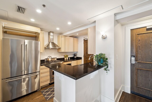 kitchen with visible vents, wall chimney range hood, appliances with stainless steel finishes, recessed lighting, and dark wood-type flooring