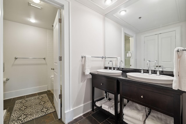 bathroom with a sink, baseboards, double vanity, and a shower