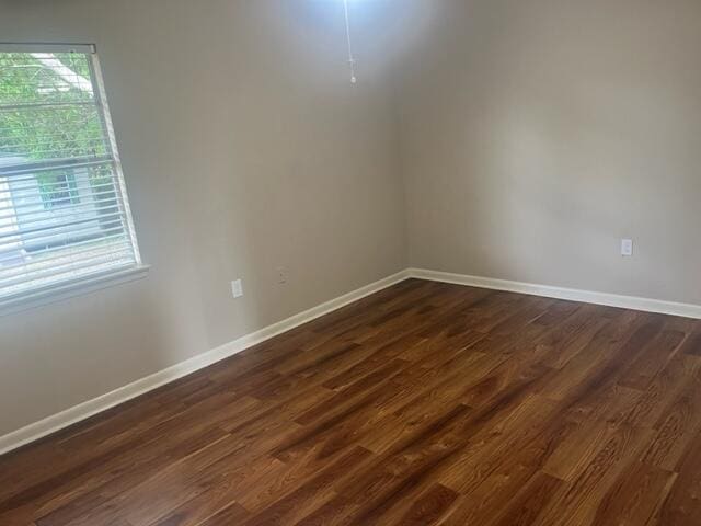 empty room with baseboards and dark wood-style floors