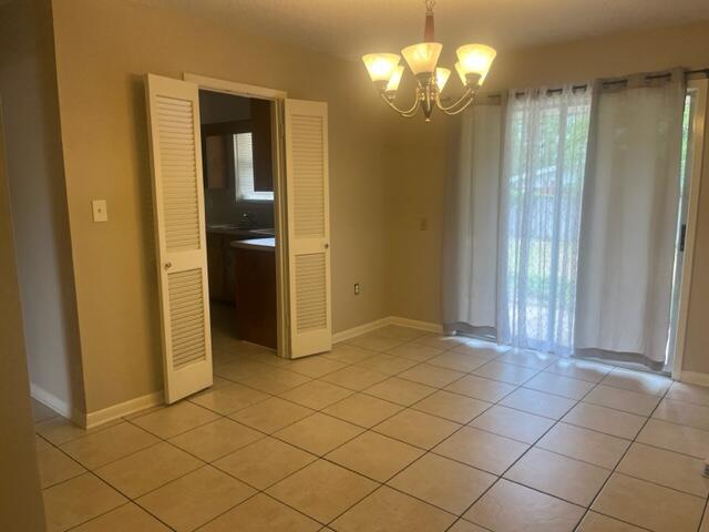 interior space with baseboards, light tile patterned flooring, and a notable chandelier