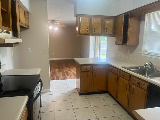 kitchen with a sink, a ceiling fan, a peninsula, under cabinet range hood, and black appliances