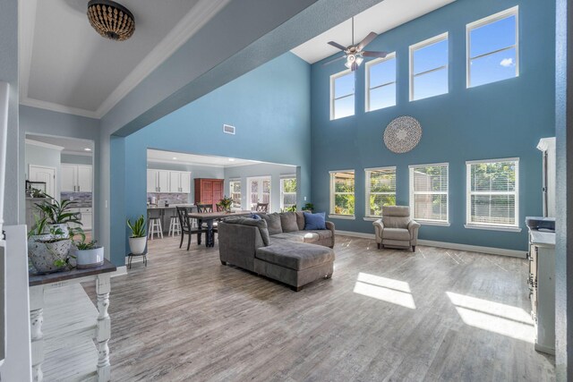730 Cornelia St, Freeport, FL 32439 - living room with light wood-type flooring, ceiling fan, crown molding, baseboards, and a towering ceiling