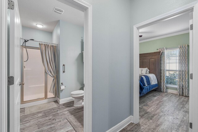 730 Cornelia St, Freeport, FL 32439 - ensuite bathroom with a shower stall, wood finished floors, baseboards, toilet, and crown molding