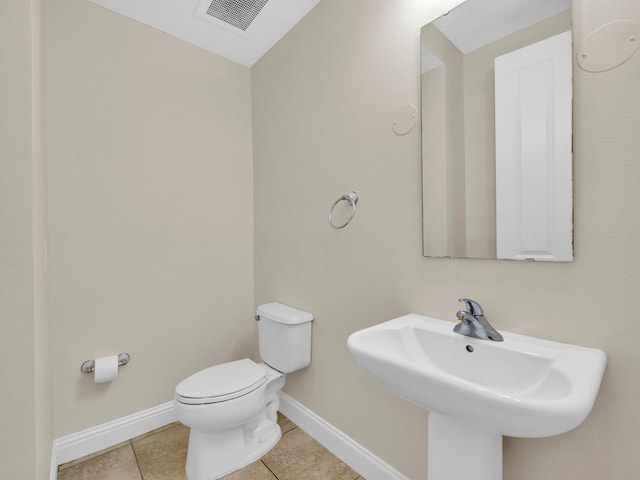 half bath featuring visible vents, baseboards, a sink, toilet, and tile patterned flooring