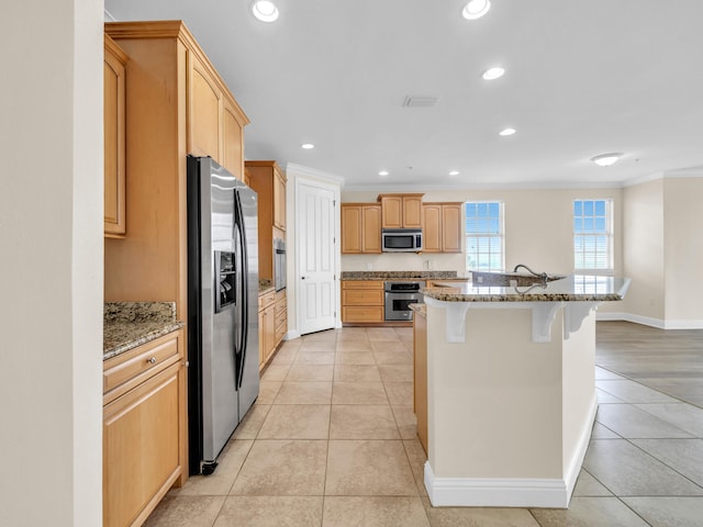 kitchen featuring a kitchen bar, light brown cabinetry, ornamental molding, and stainless steel appliances