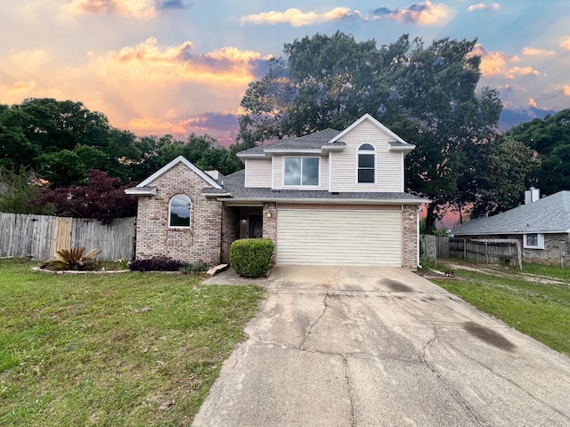 traditional-style home with a yard, brick siding, fence, and a garage