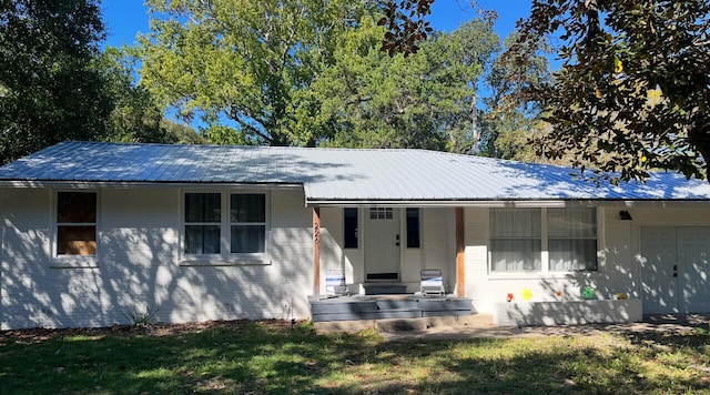 ranch-style house with metal roof, a front lawn, and covered porch