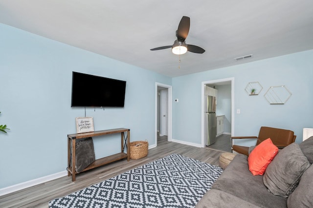 living area featuring visible vents, baseboards, a ceiling fan, and wood finished floors