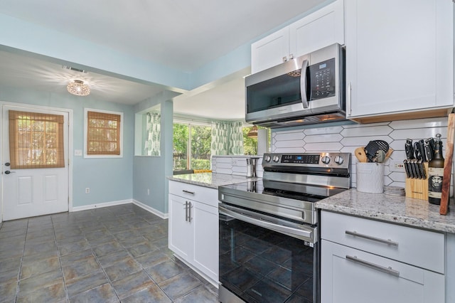 kitchen with tasteful backsplash, baseboards, white cabinetry, light stone countertops, and stainless steel appliances