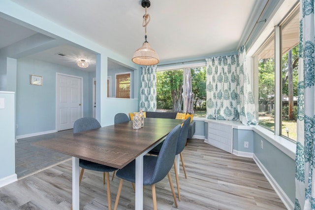 dining space with light wood-style flooring, baseboards, visible vents, and a wealth of natural light