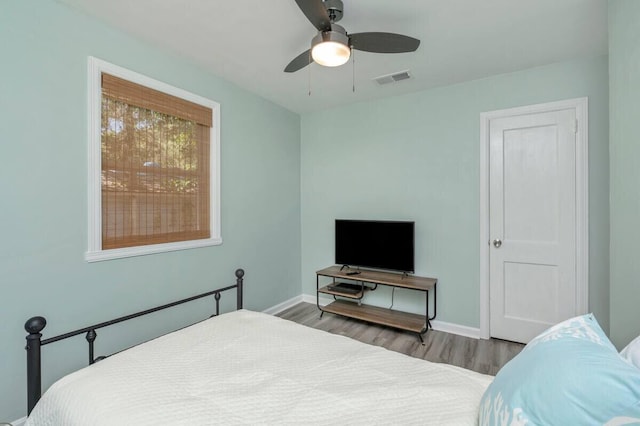 bedroom featuring visible vents, baseboards, a ceiling fan, and wood finished floors