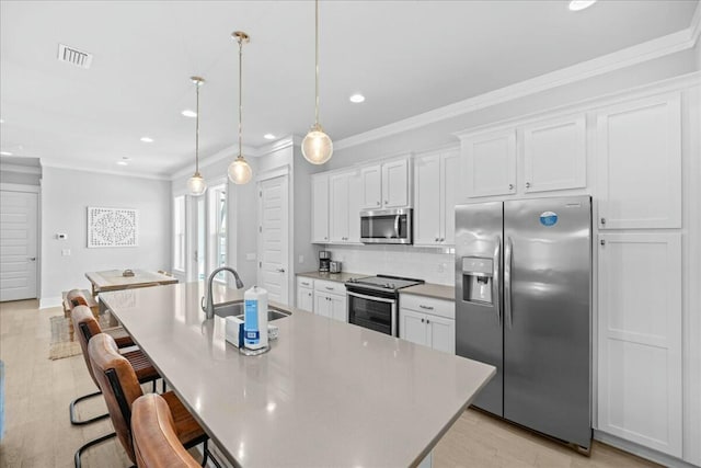 186 Ciboney St, Miramar Beach, FL 32550 - kitchen with white cabinets, a sink, ornamental molding, appliances with stainless steel finishes, and a center island with sink