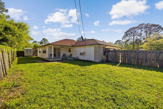 back of house with a fenced backyard, a storage unit, an outdoor structure, and a lawn