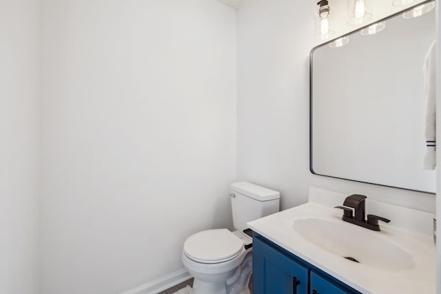 bathroom with toilet, vanity, and baseboards