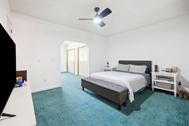 carpeted bedroom featuring arched walkways, baseboards, and a ceiling fan