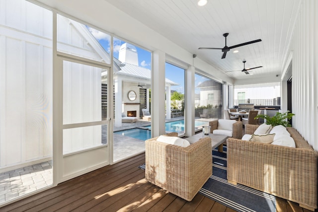 sunroom / solarium featuring an outdoor living space with a fireplace, a ceiling fan, and outdoor dining area