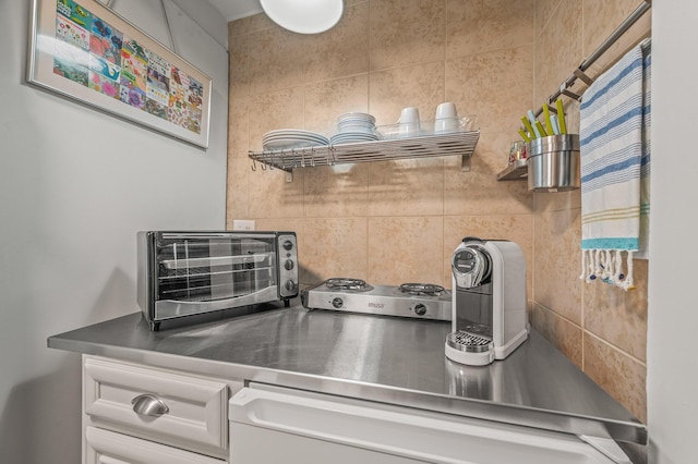 interior details featuring a toaster, backsplash, and stainless steel counters