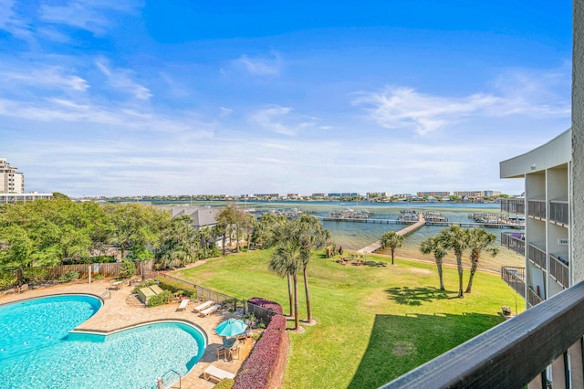 community pool featuring a yard, fence, a patio, and a water view