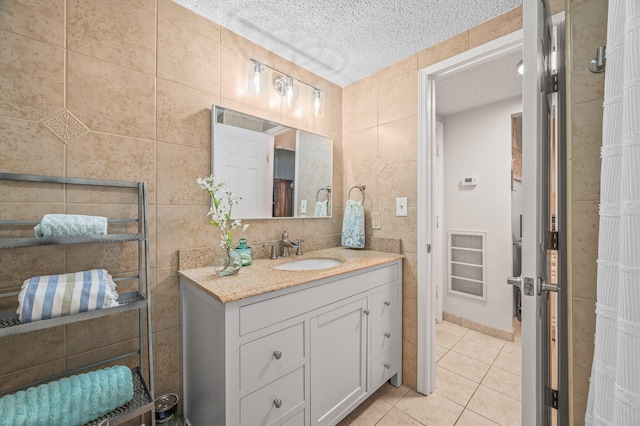 bathroom with vanity, tile patterned flooring, a textured ceiling, visible vents, and tile walls