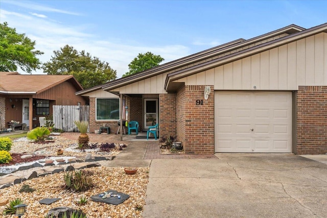 view of front facade featuring a garage, brick siding, fence, and concrete driveway