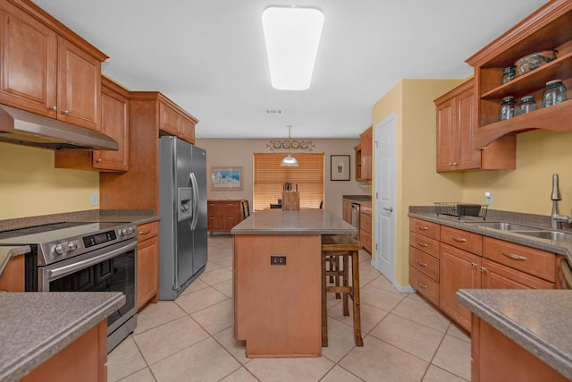 kitchen featuring a kitchen bar, a center island, under cabinet range hood, a sink, and stainless steel appliances