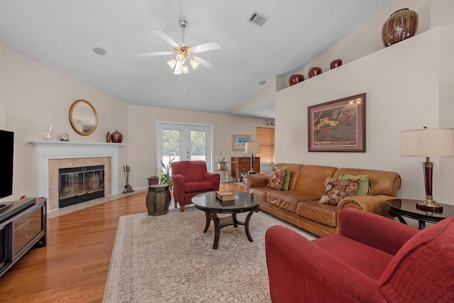 living area featuring ceiling fan, a fireplace, visible vents, lofted ceiling, and light wood finished floors