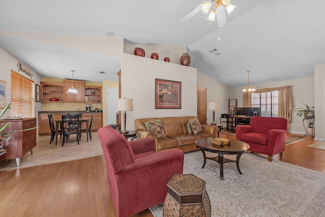 living area featuring light wood-type flooring, vaulted ceiling, and ceiling fan with notable chandelier